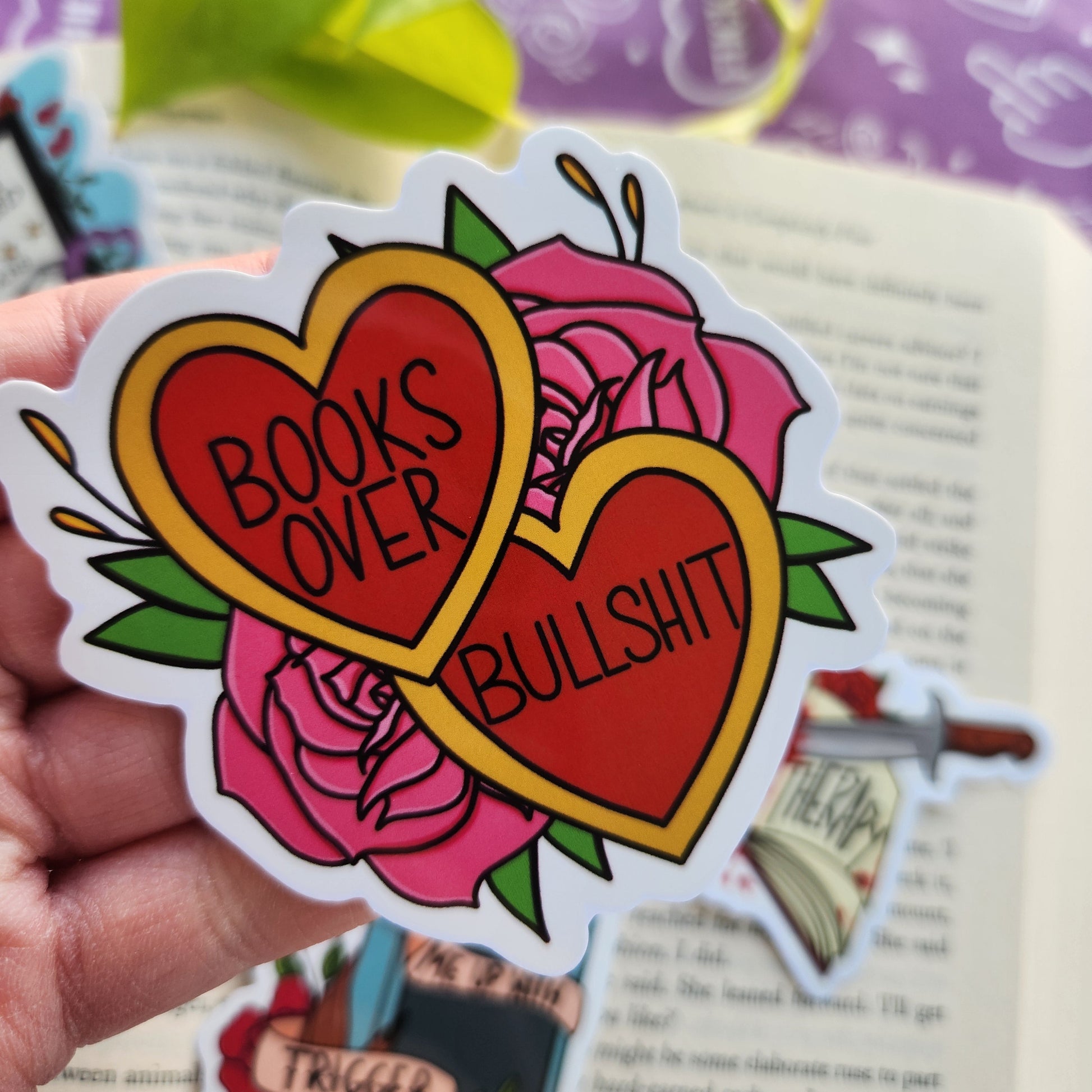 Sassy Bookish Sticker with heart design and text held by a hand on a magazine background